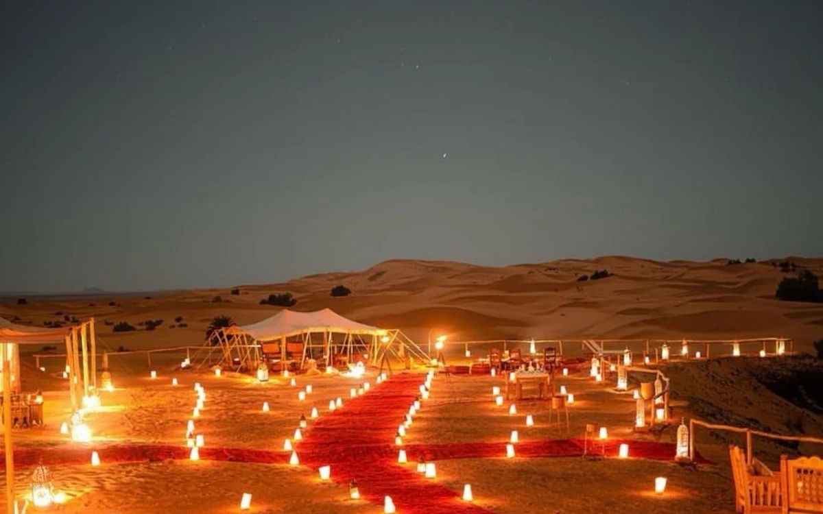 A desert camp lit up at night on the sand
