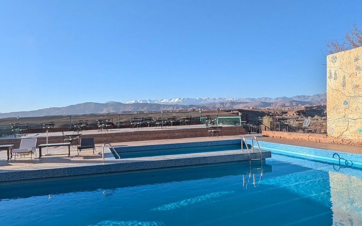 Pool terrace with loungers and tables, snow on the High Atlas behind